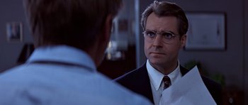 Movie still from “Clear and Present Danger” (1994), directed by Phillip Noyce – A man in a suit looking at himself in the mirror; Close Up shot, Over the shoulder angle