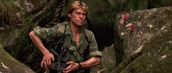 Movie still from “Clear and Present Danger” (1994), directed by Phillip Noyce – A man holding a rifle in a forest; Medium shot, Low angle