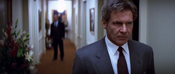 Movie still from “Clear and Present Danger” (1994), directed by Phillip Noyce – A man in a suit and tie standing in a hallway; Close Up shot, Low angle