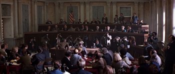 Movie still from “Clear and Present Danger” (1994), directed by Phillip Noyce – A group of people sitting in front of an american flag; Extreme Wide shot, High angle
