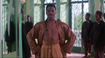 Movie still from “Coming to America” (1988), directed by John Landis – A man in a robe stands with his hands on his hips; Medium shot, Low angle