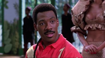 Movie still from “Coming to America” (1988), directed by John Landis – A man with a red shirt and a braid in a forest; Close Up shot, Over the shoulder angle