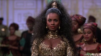 Movie still from “Coming to America” (1988), directed by John Landis – A woman in a gold dress with long black hair; Close Up shot, Low angle