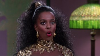 Movie still from “Coming to America” (1988), directed by John Landis – A woman in a gold dress and a gold necklace; Close Up shot, Low angle