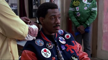 Movie still from “Coming to America” (1988), directed by John Landis – A black man getting his hair cut in a barber shop; Close Up shot, Over the shoulder angle