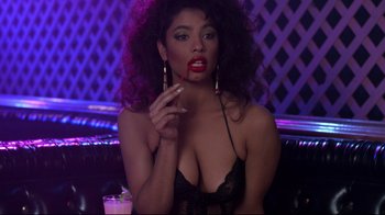 Movie still from “Coming to America” (1988), directed by John Landis – A woman in a black bra is smoking a cigarette in a bar; Close Up shot, High angle