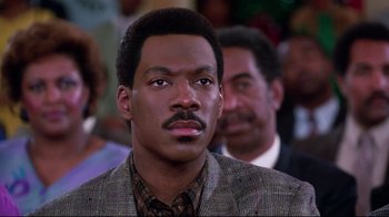 Movie still from “Coming to America” (1988), directed by John Landis – A person wearing a suit and tie; Close Up shot, Low angle
