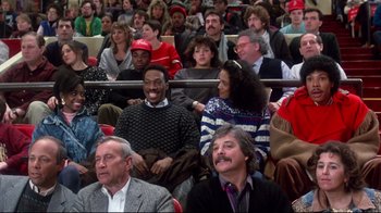 Movie still from “Coming to America” (1988), directed by John Landis – A group of people sitting in a crowd at a sporting event; Medium shot, High angle