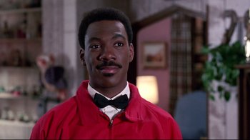 Movie still from “Coming to America” (1988), directed by John Landis – A person wearing a jacket and a bow tie; Close Up shot, Over the shoulder angle