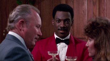 Movie still from “Coming to America” (1988), directed by John Landis – A man wearing a red jacket and a bow tie; Medium shot, Over the shoulder angle