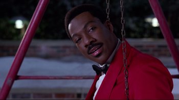 Movie still from “Coming to America” (1988), directed by John Landis – A man in a red jacket and a black bow tie; Close Up shot, Low angle
