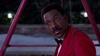 Movie still from “Coming to America” (1988), directed by John Landis – A man in a red jacket and a black bow tie; Close Up shot, Low angle