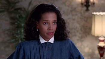 Movie still from “Coming to America” (1988), directed by John Landis – A young woman with long black curly hair wearing a blue shirt; Close Up shot, Over the shoulder angle