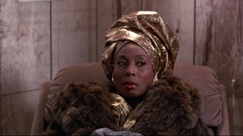 Movie still from “Coming to America” (1988), directed by John Landis – A black woman with a gold head wrap and fur jacket; Close Up shot, Low angle