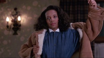 Movie still from “Coming to America” (1988), directed by John Landis – A woman in a blue shirt is holding a coat; Medium shot, Over the shoulder angle