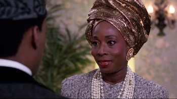 Movie still from “Coming to America” (1988), directed by John Landis – An older woman wearing a head scarf and pearls; Close Up shot, Over the shoulder angle