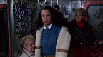 Movie still from “Coming to America” (1988), directed by John Landis – A woman sitting on a train with a fur coat on; Medium shot, Over the shoulder angle