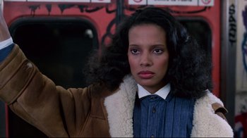 Movie still from “Coming to America” (1988), directed by John Landis – A woman in a blue shirt and a brown jacket; Close Up shot, Low angle