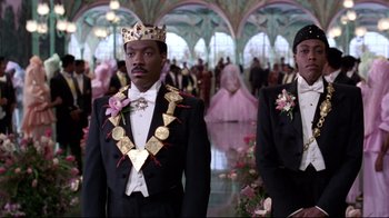 Movie still from “Coming to America” (1988), directed by John Landis – Two men in tuxedos are standing in a ballroom; Medium shot, Low angle