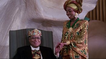 Movie still from “Coming to America” (1988), directed by John Landis – A man and a woman in a chair wearing a crown; Medium shot, Low angle