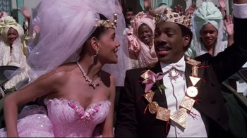 Movie still from “Coming to America” (1988), directed by John Landis – A man and a woman wearing crowns and smiling; Medium shot, Low angle