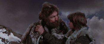 Movie still from “Conan the Barbarian” (1982), directed by John Milius – A man with a beard is holding a little girl; Close Up shot, Low angle