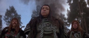 Movie still from “Conan the Barbarian” (1982), directed by John Milius – A man with long black hair wearing a black and brown outfit; Close Up shot, Low angle