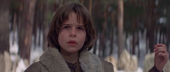 Movie still from “Conan the Barbarian” (1982), directed by John Milius – A young boy wearing a fur coat looking at the camera; Close Up shot, Low angle