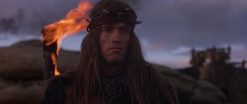 Movie still from “Conan the Barbarian” (1982), directed by John Milius – A person with long brown hair; Close Up shot, Low angle