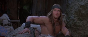 Movie still from “Conan the Barbarian” (1982), directed by John Milius – A man with long brown hair and a headband on; Medium shot, High angle