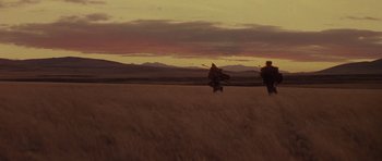 Movie still from “Conan the Barbarian” (1982), directed by John Milius – Two people are flying kites in a field at sunset; Extreme Wide shot, Low angle