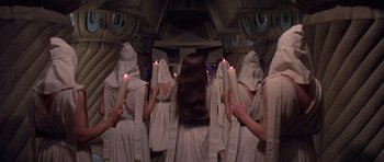 Movie still from “Conan the Barbarian” (1982), directed by John Milius – A group of people dressed in white holding lit candles; Wide shot, High angle