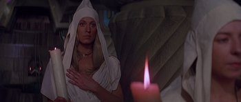 Movie still from “Conan the Barbarian” (1982), directed by John Milius – A woman in a white robe and a candle in the background; Medium shot, High angle