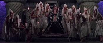 Movie still from “Conan the Barbarian” (1982), directed by John Milius – A group of people in white robes and a man in black; Wide shot, High angle