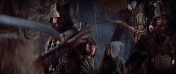 Movie still from “Conan the Barbarian” (1982), directed by John Milius – A group of people standing next to each other in a room; Medium shot, Over the shoulder angle