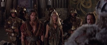 Movie still from “Conan the Barbarian” (1982), directed by John Milius – A group of men and women dressed in costumes; Medium shot, Over the shoulder angle