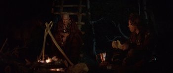 Movie still from “Conan the Barbarian” (1982), directed by John Milius – An old man sitting in a dark room; Wide shot, High angle