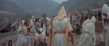 Movie still from “Conan the Barbarian” (1982), directed by John Milius – A group of people gathered in the desert; Wide shot, High angle