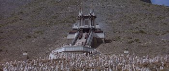 Movie still from “Conan the Barbarian” (1982), directed by John Milius – A group of people standing on top of a hill; Extreme Wide shot, High angle