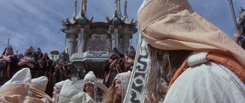 Movie still from “Conan the Barbarian” (1982), directed by John Milius – A group of people standing in front of a building; Wide shot, High angle
