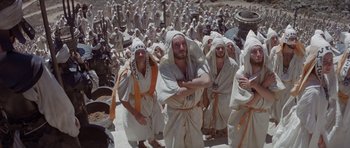 Movie still from “Conan the Barbarian” (1982), directed by John Milius – A group of men in white robes standing next to each other; Wide shot, High angle