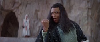 Movie still from “Conan the Barbarian” (1982), directed by John Milius – A man with long black hair is wearing a wig; Close Up shot, Low angle