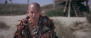 Movie still from “Conan the Barbarian” (1982), directed by John Milius – A bald man with a beard wearing a costume; Medium shot, Low angle