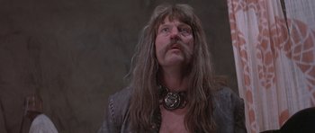 Movie still from “Conan the Barbarian” (1982), directed by John Milius – A person with long hair and a beard; Close Up shot, Low angle