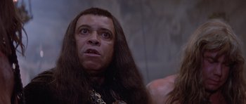 Movie still from “Conan the Barbarian” (1982), directed by John Milius – A person with long hair; Close Up shot, Over the shoulder angle
