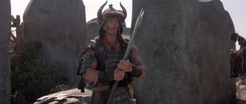 Movie still from “Conan the Barbarian” (1982), directed by John Milius – A man dressed as a viking holding a spear; Medium shot, Low angle