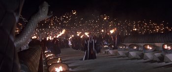 Movie still from “Conan the Barbarian” (1982), directed by John Milius – A group of people are standing in the dark with torches in their hands; Extreme Wide shot, High angle