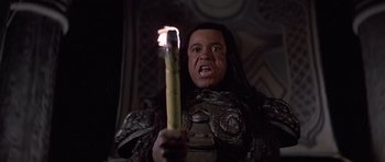 Movie still from “Conan the Barbarian” (1982), directed by John Milius – A man holding a lit candle in front of a dark background; Close Up shot, High angle