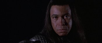 Movie still from “Conan the Barbarian” (1982), directed by John Milius – A man's face with long black hair; Close Up shot, High angle