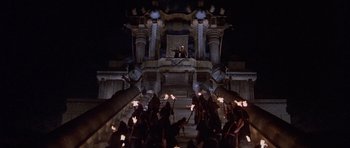 Movie still from “Conan the Barbarian” (1982), directed by John Milius – A group of people standing on top of a building; Extreme Wide shot, High angle